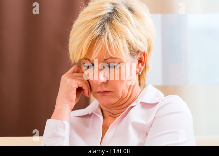 Vecchia donna tocca la fronte di mal di testa o emicrania Foto Stock