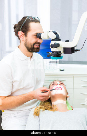 Dentista usando microscopio per controllare i denti del paziente Foto Stock