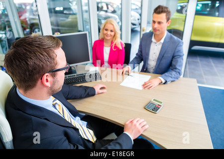Giovane acquisto auto presso la concessionaria e negoziare il prezzo con il venditore Foto Stock