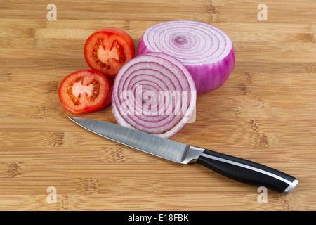 Ingrandimento orizzontale della foto appena cipolla rossa affettata e pomodoro con coltello da cucina nella parte anteriore e di bamboo naturale sotto legno Foto Stock