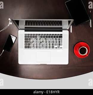 Macbook Apple computer portatile, iPhone Kindle tablet e un rosso tazza di caffè su una scrivania. Lavorare o studiare il concetto di ambiente. Foto Stock