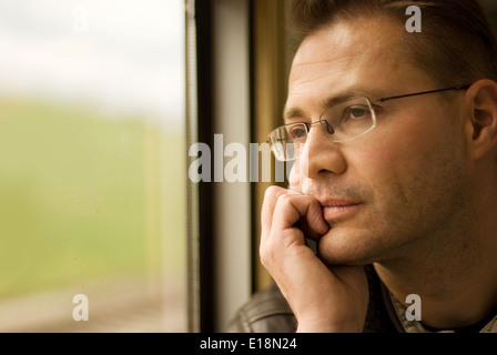 Uomo di pensiero cercando in una finestra Foto Stock