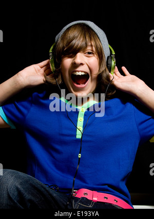 Ragazzo adolescente ascoltando musica ad alto volume sulle cuffie e cantare insieme Foto Stock