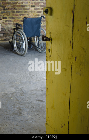 Sedia a rotelle vuota nella vecchia cantina Foto Stock