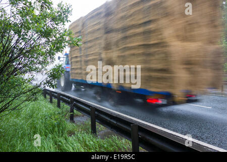 Il trattore con il rimorchio di balle di fieno in pesante Rush Hour pioggia sulla A19 a Billingham, a nord-est dell' Inghilterra Foto Stock