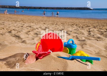 Benna con plastica giocattoli da spiaggia in sabbia sulla riva del mare Foto Stock