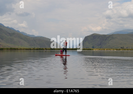 Un uomo Stand Up Paddle Boarding (SUP) con i suoi figli sulla Laguna Huacarapay, nel vicino a Cusco, Perù Foto Stock