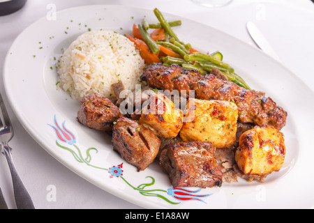 Mescolato pollo, agnello adana shish kebab servite su gyro döner con riso pilaf e guarnito con verdure verdi, Foto Stock