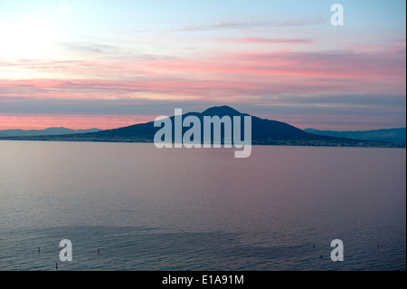 Cielo rosso dietro il Monte Vesuvio, un vulcano attivo, in vista di tutta la baia di Napoli da Sorrento al tramonto Foto Stock