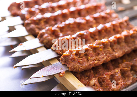 Diversi Adana kebab spiedini schierate in attesa di essere cucinati e serviti Foto Stock