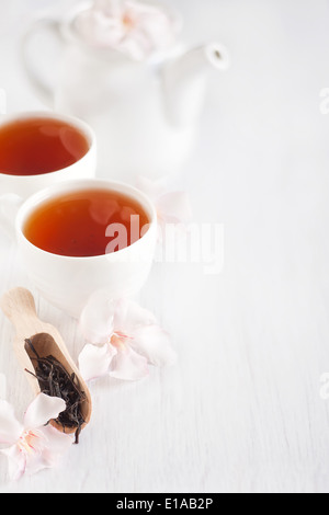 Tè Oolong in uno scoop, tazze e teiera con light rose fiori di rododendro. Copia di sfondo spazio. Foto Stock