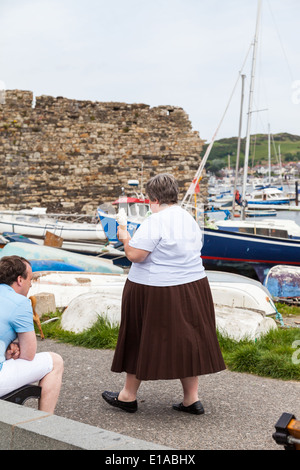 Sopra il peso donna, passeggiate, tenendo in mano un cono gelato in mano.Conway, Galles, Gran Bretagna. Foto Stock