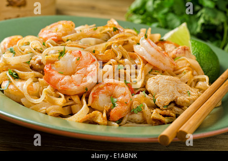 Una piastra di piccante pad thai con pollo e gamberetti con bacchette. Foto Stock