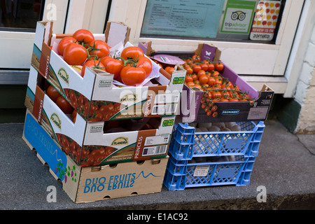 Pomodori freschi sulla vite e funghi nelle caselle al di fuori di un negozio porta Foto Stock