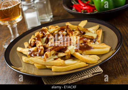 Un piatto di deliziosa poutine con patate fritte, salsa, e cagliata del formaggio. Foto Stock