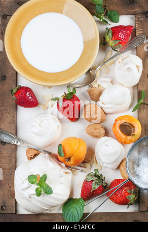 Meringa fatti in casa con Albicocche Fragole, mandorle e crema. Ingredienti per il dessert Eton mess. Vista dall'alto. Foto Stock