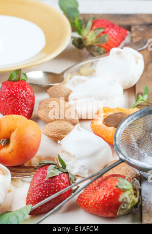 Meringa fatti in casa con Albicocche Fragole, mandorle e crema. Ingredienti per il dessert Eton mess. Foto Stock