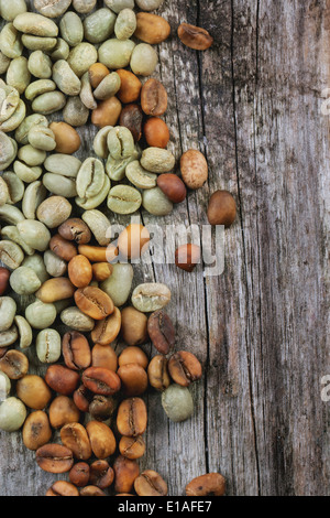 Verde e marrone caffè decaffeinato caffè non torrefatto fagioli su sfondo di legno. Foto Stock