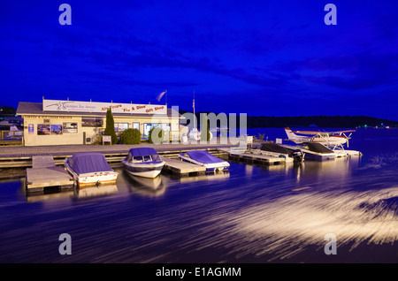 Un piano di flottazione e barche a motore legato alla riva al tramonto davanti a 'Georgian Bay Airways'. Parry Sound Harbour, Ontario, Canada. Foto Stock