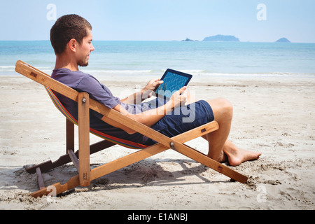 Business man lavora con la compressa sulla spiaggia Foto Stock