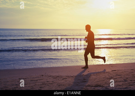 Uno stile di vita sano, silhouette di runner sulla spiaggia Foto Stock