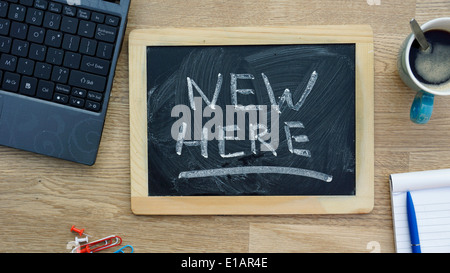 Nuovo qui scritto su una lavagna in ufficio Foto Stock