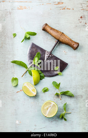 Ingredienti per rendere i mojito con foglie di menta e calce su sfondo blu Foto Stock