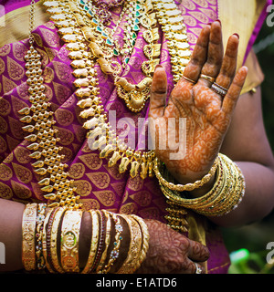 Le mani di un indiano sposa adornata con gioielli, schiave e verniciati con colore henné Foto Stock