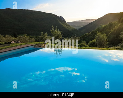 I trend con orizzonte di riferimento e riflessioni in una piscina infinity contro un luminoso cielo del pomeriggio Foto Stock