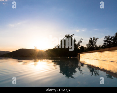 I trend con orizzonte di riferimento e riflessioni in una piscina infinity contro un Cielo di tramonto Foto Stock