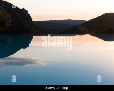 I trend con orizzonte di riferimento e riflessioni in una piscina infinity contro un Cielo di tramonto Foto Stock