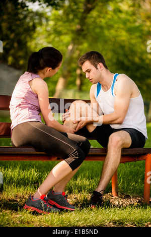 La donna aiuta a uomo che ha ferito suo vitello quando jogging Foto Stock