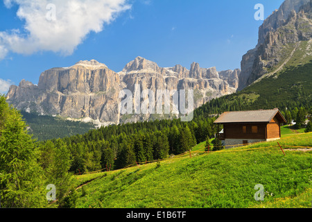 Paesaggio estivo in Val di Fassa con un piccolo chalet sotto le montagne delle Dolomiti in Trentino, Italia Foto Stock