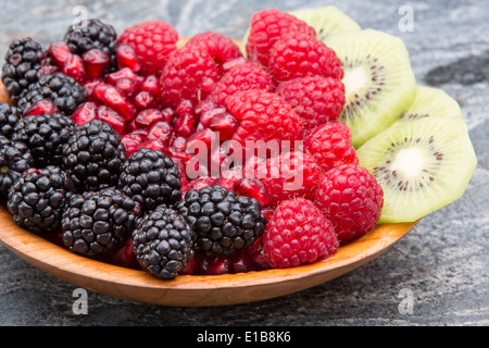 Ciotola di esotico fresco frutta tropicali con colorati file ordinate di more, i semi di melograno, lamponi e tagliate a fettine sottili Foto Stock