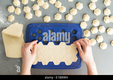 Vista aerea di una donna di preparare i ravioli di pasta fresca come lei forme decorative involucri esagonale con un ripieno gustoso di t Foto Stock