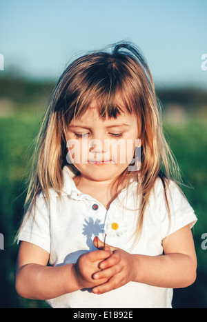 Baby girl holding piccolo fiore Foto Stock