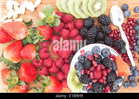 Preparazione di un sano deliziosi frutti di bosco con insalata di frutta fresca assortita sul contatore comprese le fragole, lamponi Foto Stock