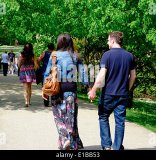 Coppia giovane camminando mano nella mano Buxton pavilion gardens Derbyshire England Regno Unito Foto Stock