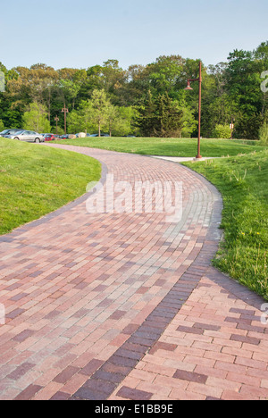 Mattone di avvolgimento giardino pavimentato percorso con erba verde a lato Foto Stock