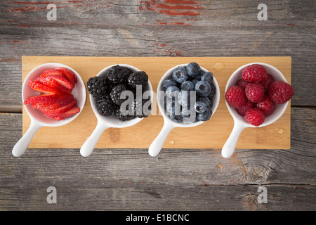 Gustosi piatti freschi frutti di bosco in autunno in una cucina rustica visto dal di sopra in piccolo degustatore piatti con tutto more mature, blueberrie Foto Stock