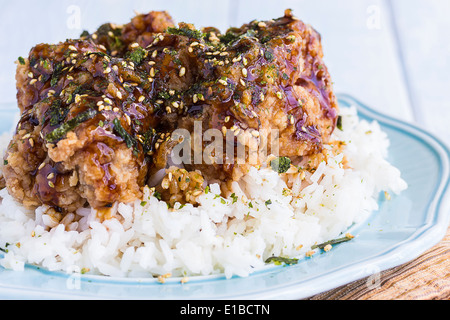 Pollo fritto coperto di aglio salsa teriyaki e spolverati con furikake su un letto di riso Foto Stock