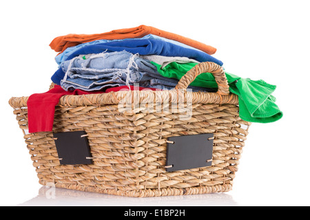Pila di coloratissimi pulire lavare indumenti freschi in un tessuto rustico cesto in vimini con etichette vuote sui lati pronti per essere stirati, Foto Stock