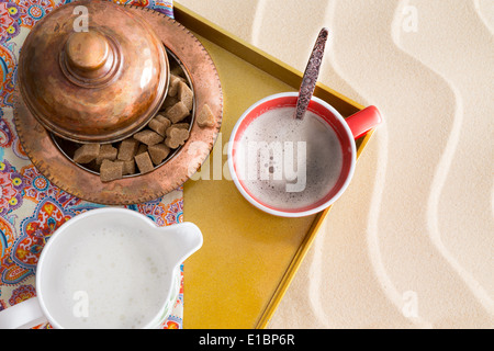 Caffè caldo servito sulla spiaggia con una vista in pianta di una caffettiera, tazza del preparato di fresco il caffè caldo e marrone e cubetti di zucchero al Foto Stock