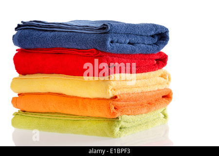 Pila di ben piegati colorato asciugamani di cotone in rosso, blu, giallo, arancio e verde su un bianco riflettente sfondo con copysp Foto Stock
