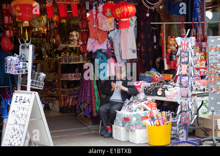 Negoziante presso il suo negozio porta a Chinatown - Newport Plc, Londra Soho - REGNO UNITO Foto Stock