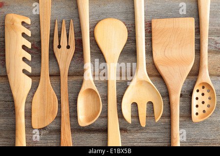 Set di rustico artigianale in legno utensili da cucina con un filtro di spaghetti, cucchiai , spatola e insalata di server disposti in un Foto Stock