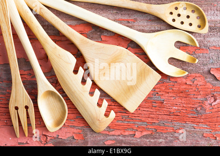 Set assortito di artigianato artistico del legno utensili da cucina disposti in una ventola dall'angolo superiore sinistro su un grunge di legno Tavolo picnic Foto Stock