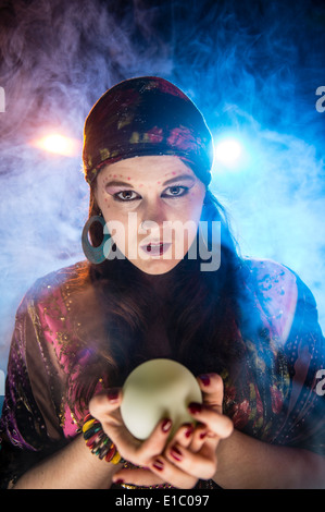 Una donna mistica gypsy Fortune teller tenendo una sfera di cristallo guardando al futuro Foto Stock