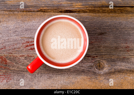 Arancione tazza ceramica piena di fresco latte caldo il caffè del mattino e rabboccato con una spuma lattiginosa , Vista aerea su un tavolo di legno con copys Foto Stock