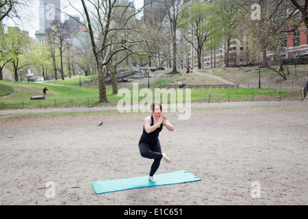 Una giovane donna in Central Park, in un nero leotard e gambali, fare yoga. Foto Stock